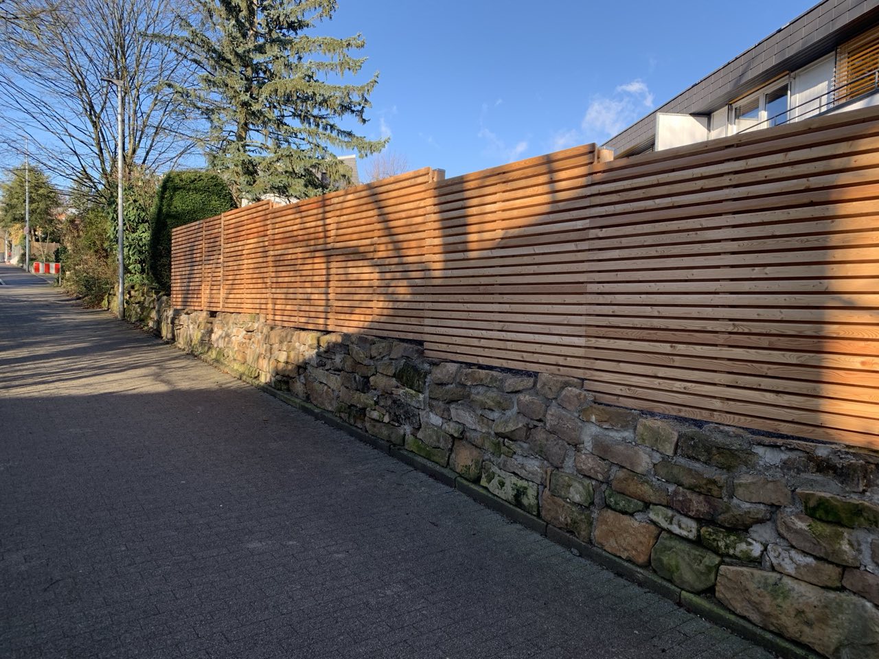 Sichtschutzzaun aus Holz mit Natursteinmauer